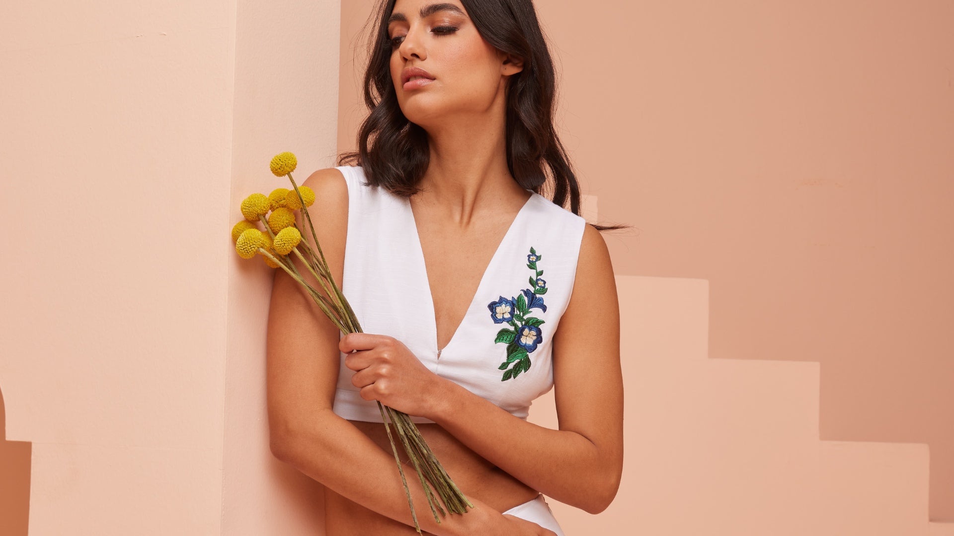 Model in White Linen, Graced with a Bouquet of Delicate Flowers in Hand.