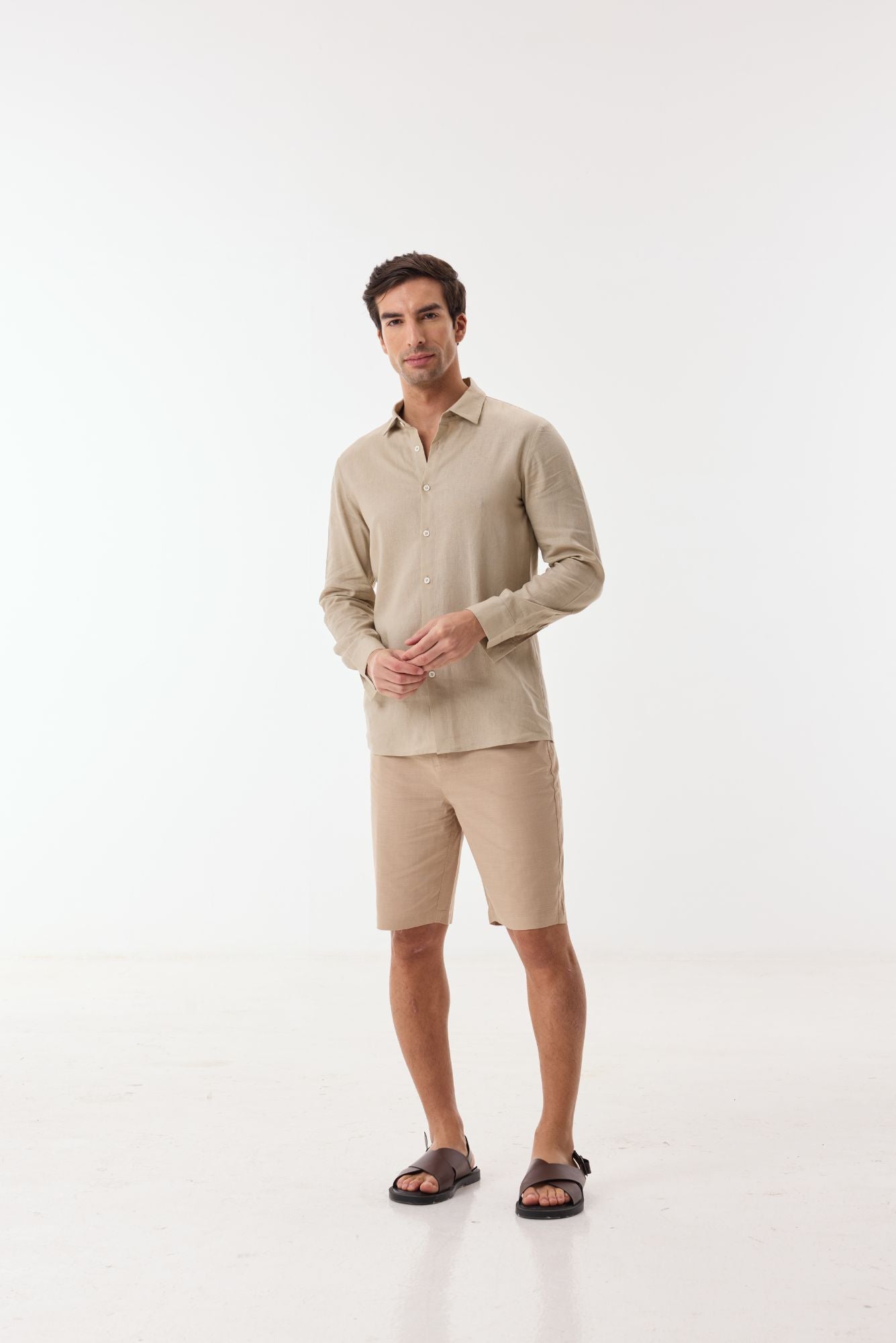 Man wearing a beige shirt and shorts on a white background